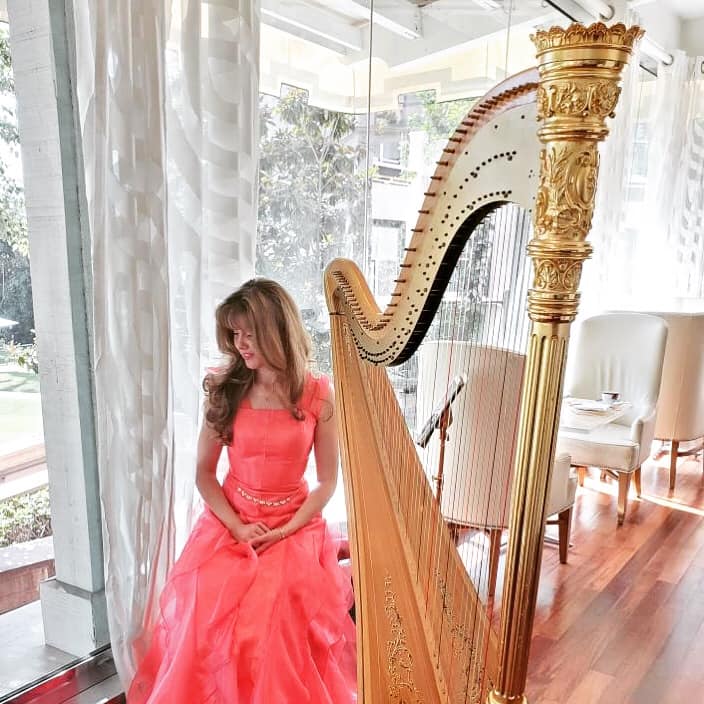 Amber performing harp music for a refined indoor event
