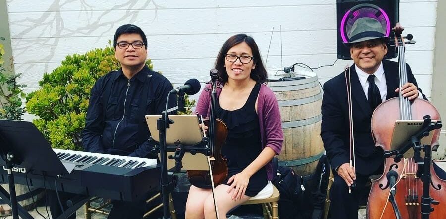 Cecile performing violin with a live trio ensemble