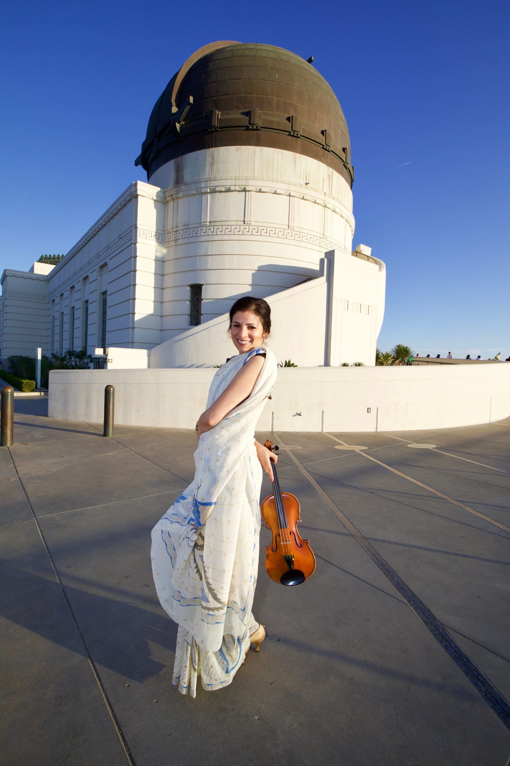 Priyanka wearing a traditional saree while holding a violin in Los Angeles