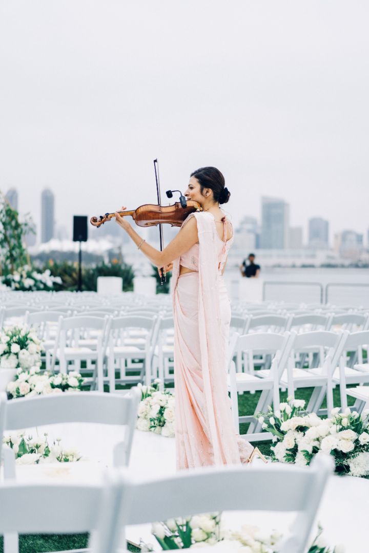 Priyanka performing violin music during an outdoor Indian wedding ceremony in Orange County