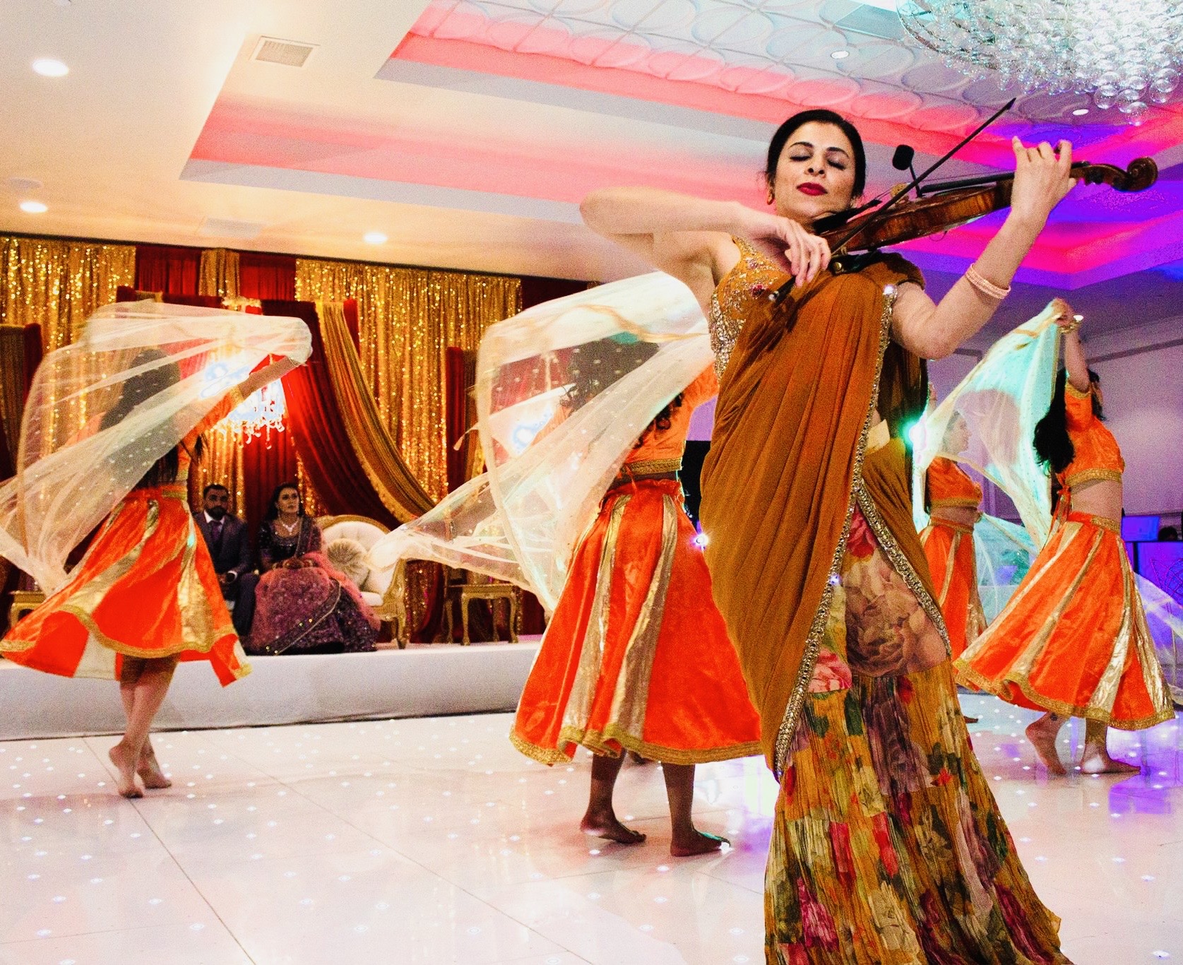 Priyanka performing violin music during an Indian wedding ceremony by the waterfront