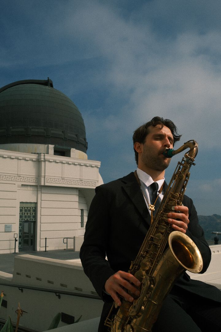 Chris playing saxophone outdoors near a Los Angeles landmark