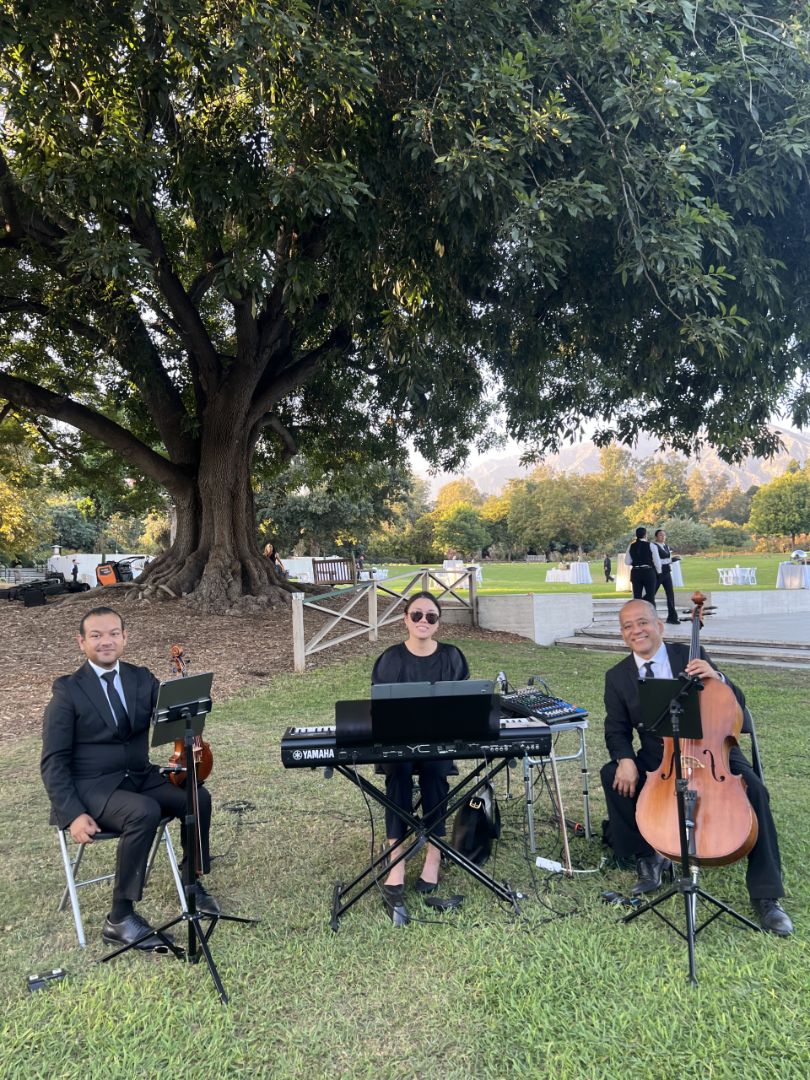 Piano, violin and cello trio performing outdoors for an Orange County wedding